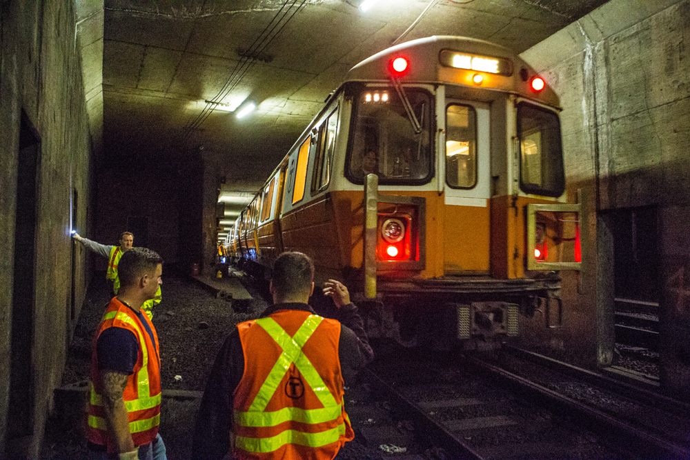Maintenance workers watch train pass in subway tunnel