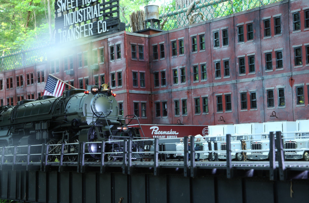 model steam locomotive near large industrial building
