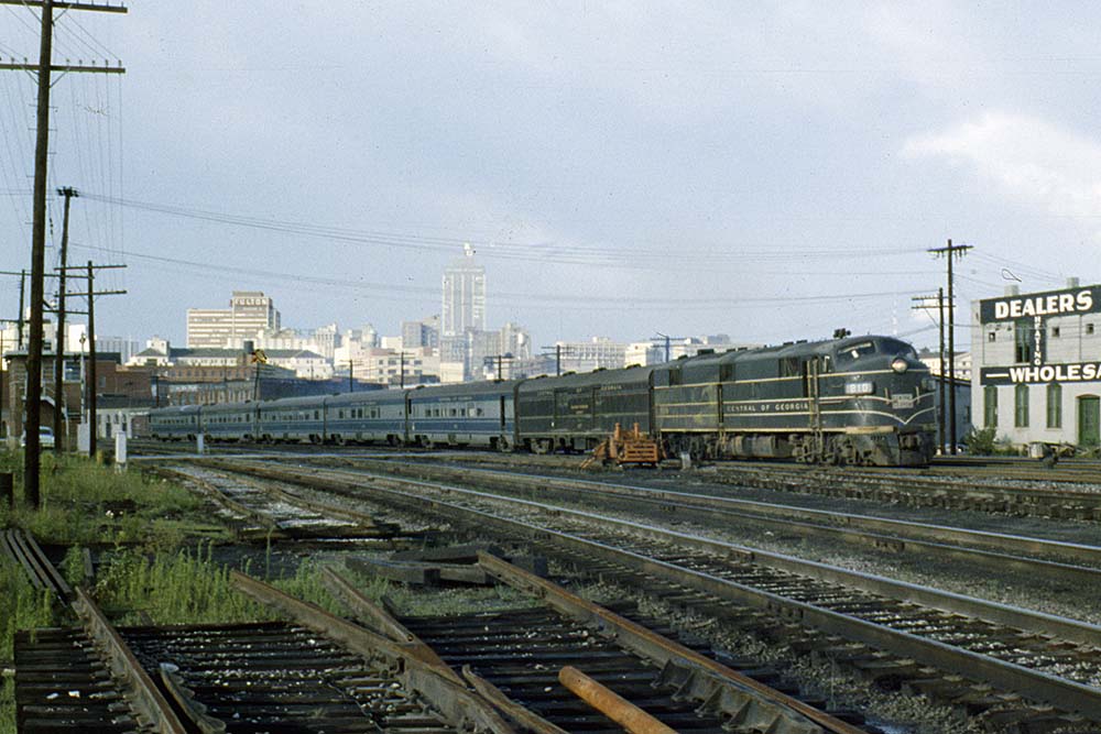 Streamlined Central of Georgia locomotive with passenger train in city