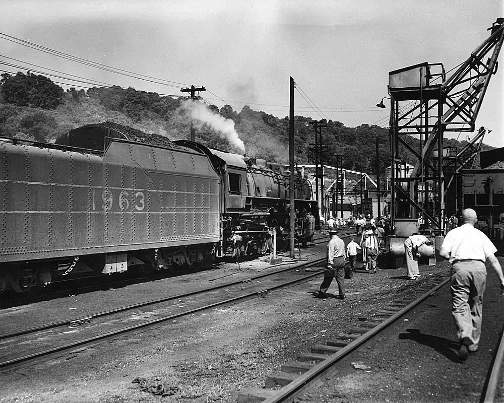 People walk around most expensive 2-8-4 steam locomotive at coaling tower