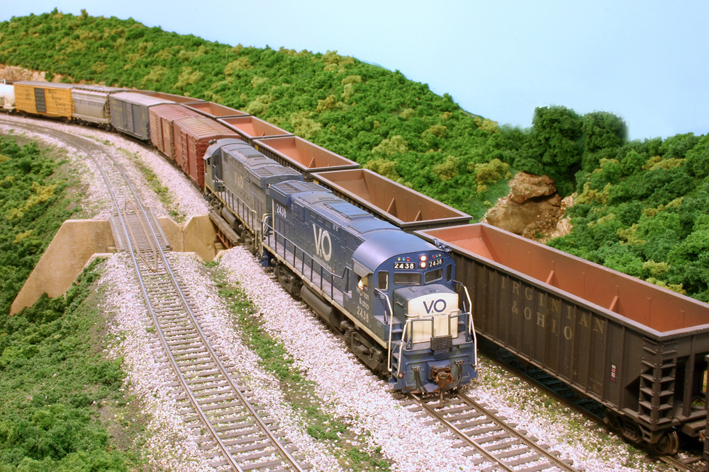 Freight train with two diesel locomotives passing empty hoppers