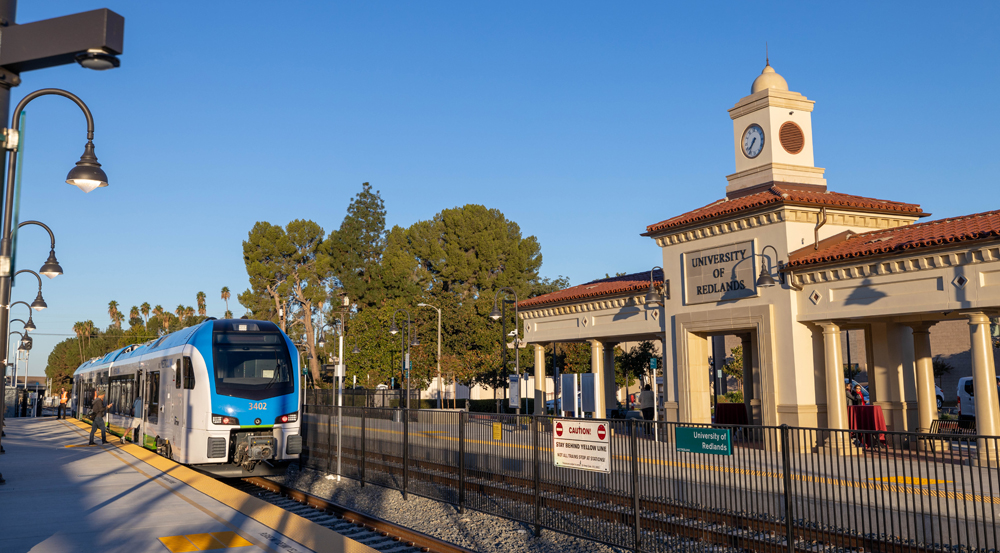 Blue and white diesel multiple-unit trainset arrives at station with clocktower