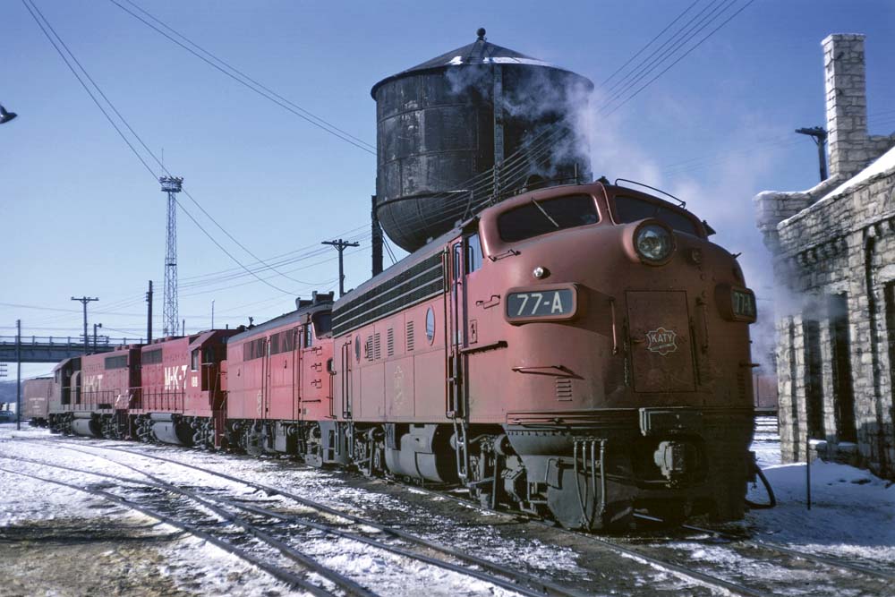 Red diesel Missouri-Kansas-Texas locomotives outside shop building