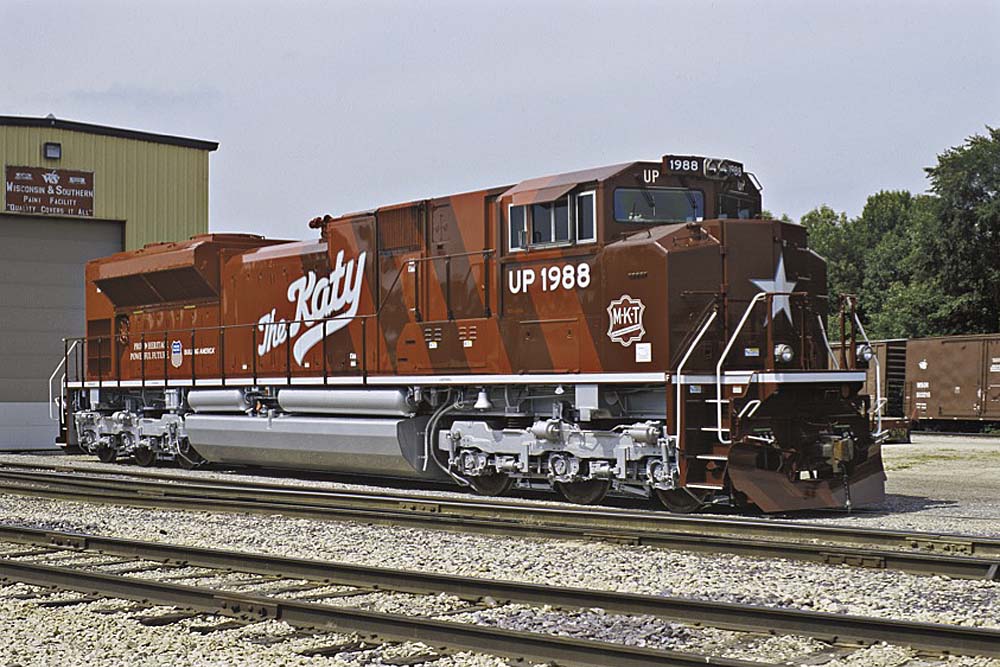 Red diesel Missouri-Kansas-Texas locomotive outside shop building