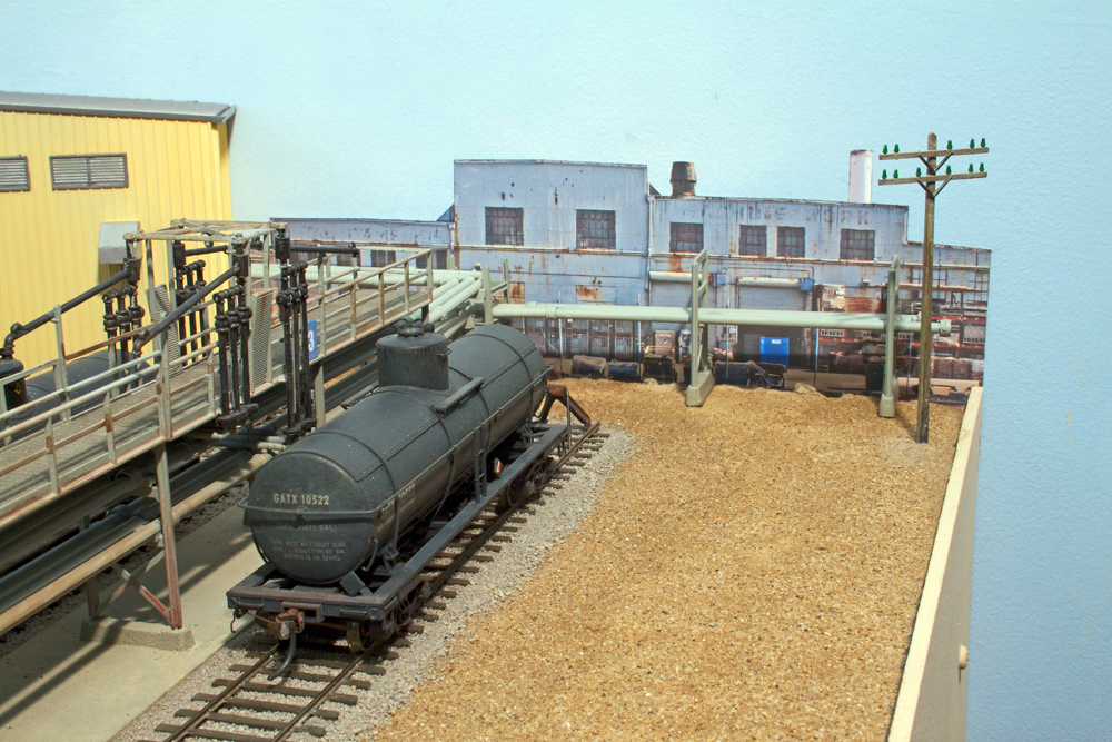 A lack tanker truck is shown alongside a yellow structure with a blue structure in the background