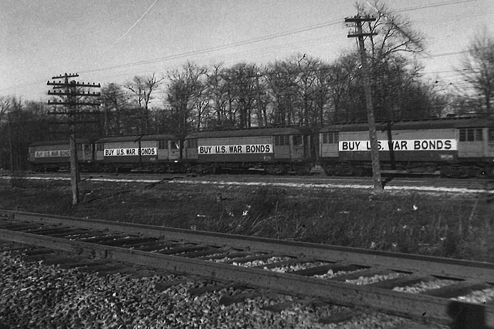 Wooden Chicago North Shore & Milwaukee equipment railcars parked on siding under wires