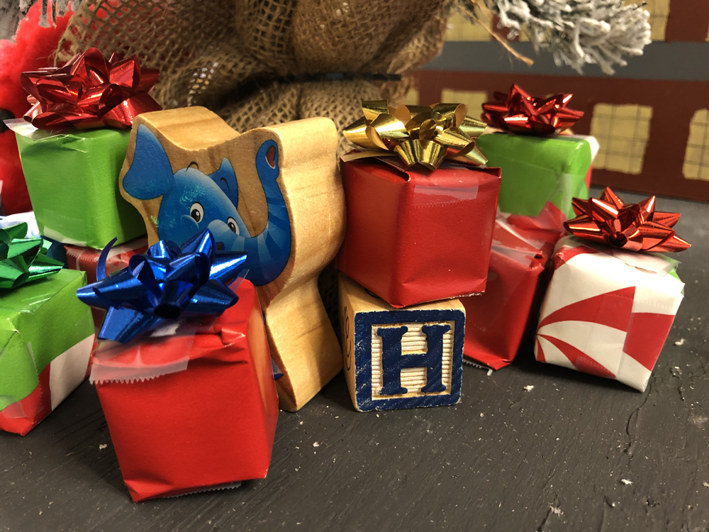 pile of small Christmas packages and a wood child’s block