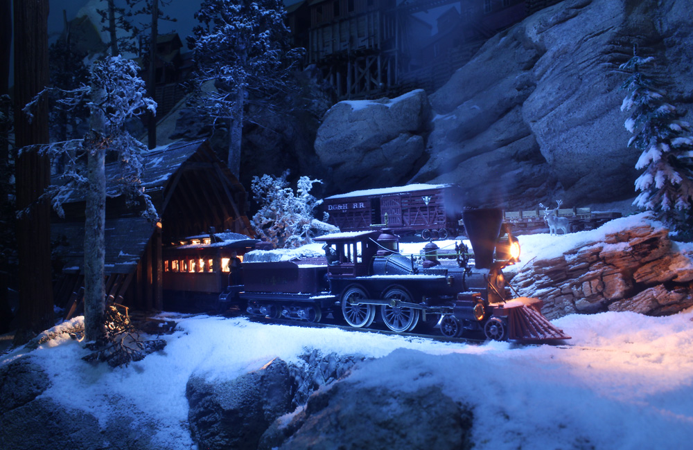 A steam locomotive with a passenger train emerges from a snow shed into a moonlit snowscape