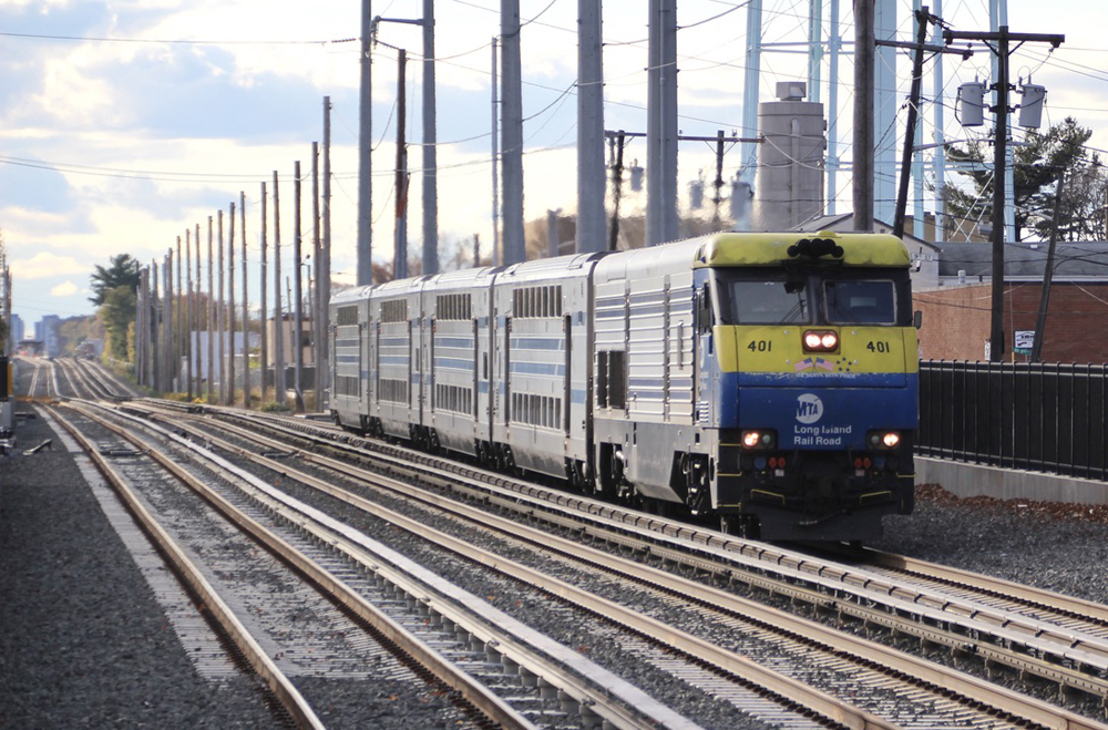 Commuter train with diesel locomotive and four bilevel cars on three-track main line