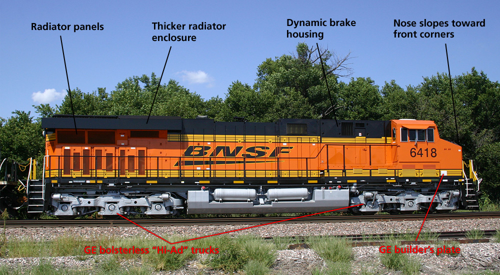 A modern General Electric diesel in orange, black, and yellow is seen in a side-on shot