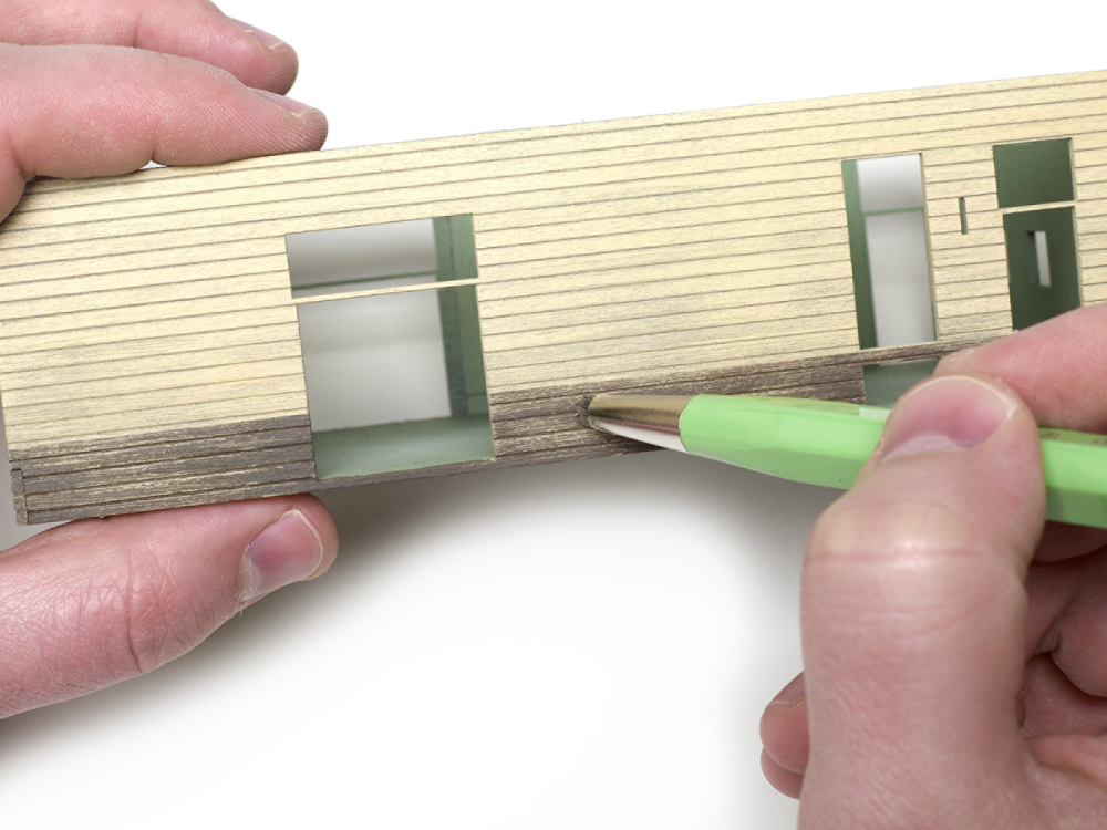An image of a distresser brush used along wooden siding.
