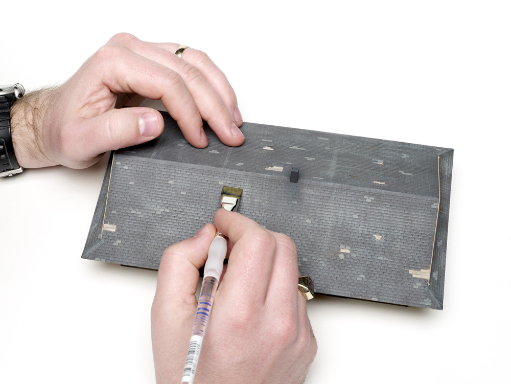 An image of a brush used on the roof of a model wood structure.