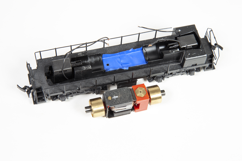 The frame of a locomotive with blue tape on the bottom and motor next to the frame