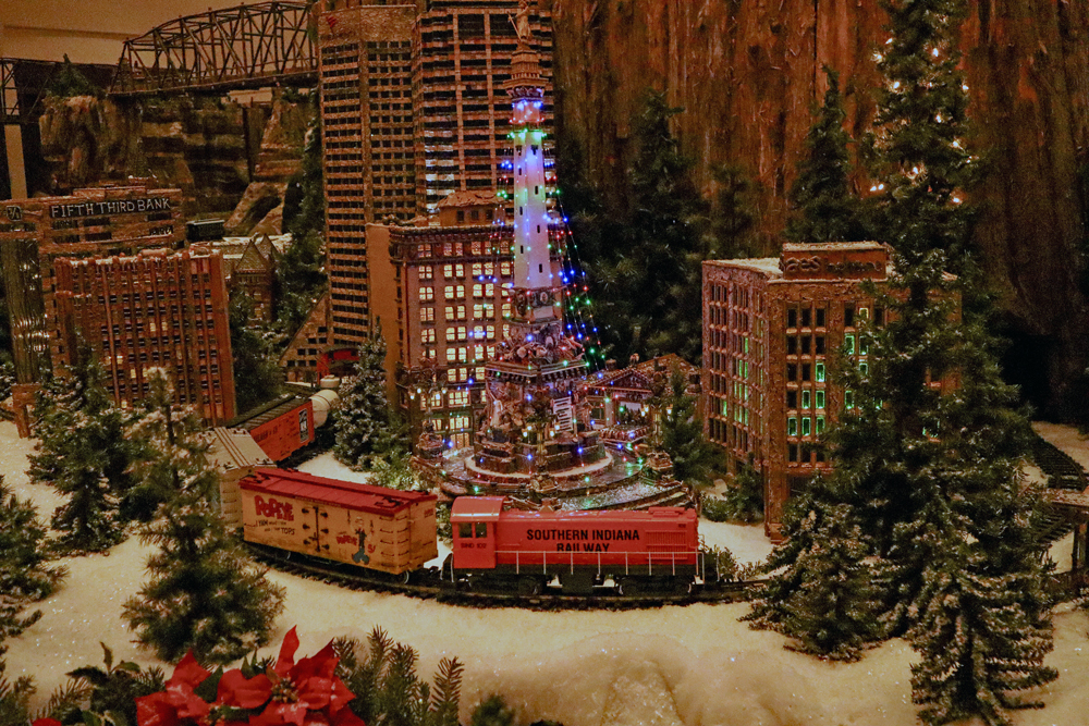 Snowy city scene with tree made from lights in the middle