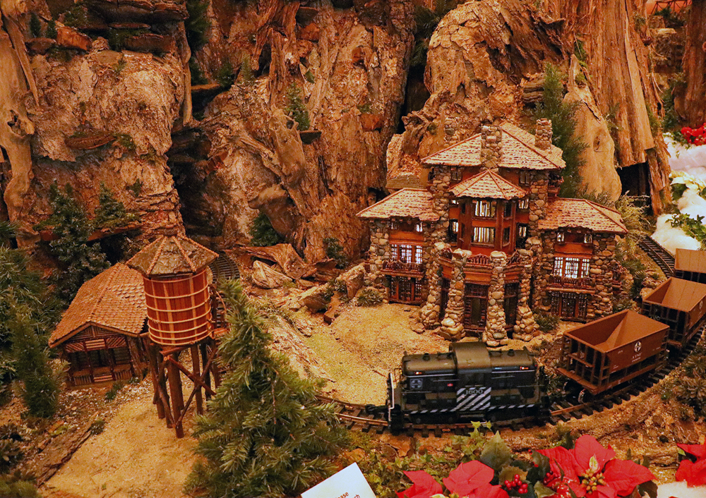 A black centercab diesel locomotive rounds a curve pulling empty hopper cars