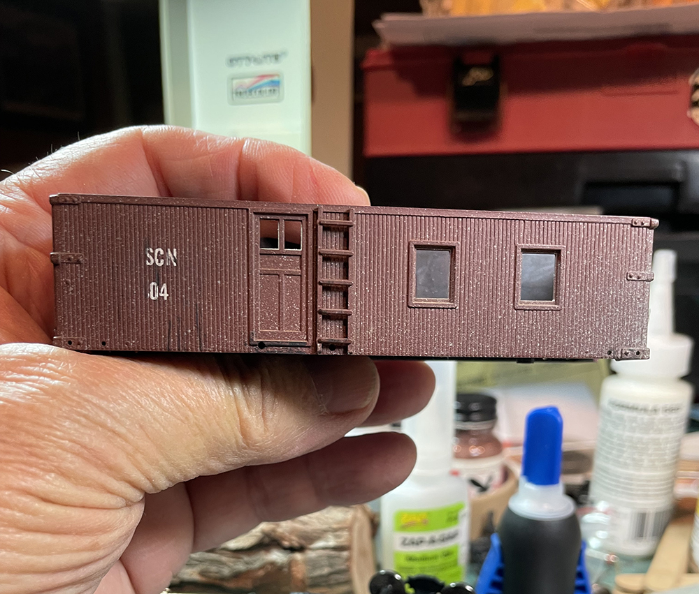 Brown model wood-sided caboose body with small white letters