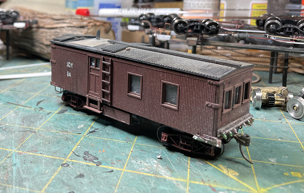 Brown model wood-sided caboose with brown windows and door and black roof