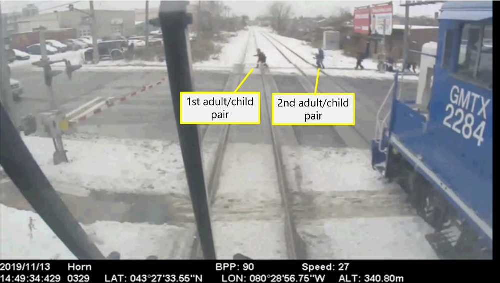 Image from camera on commuter-train cab car of people crossing street in front of train
