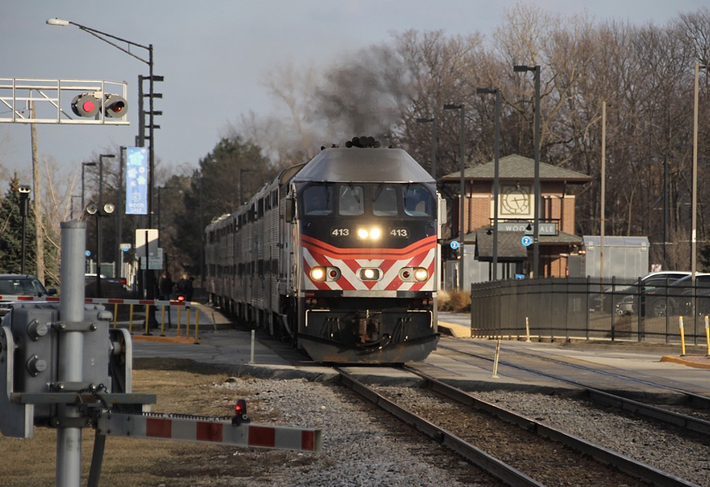 Commuter train crosses street as it leaves station