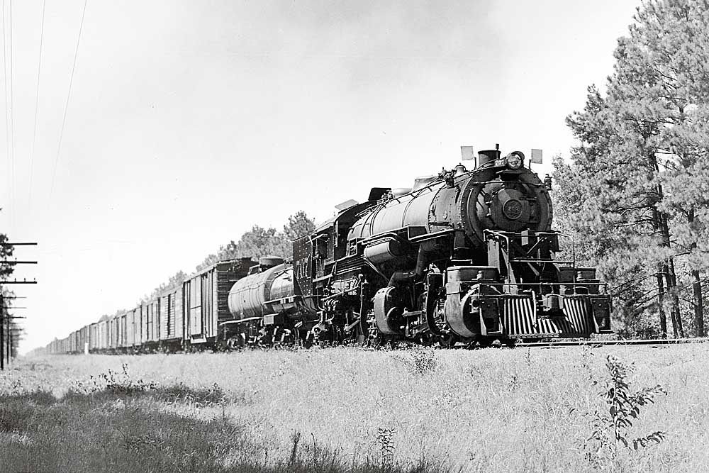 Three quarter view of steam-powered Kansas City Southern locomotives with freight train