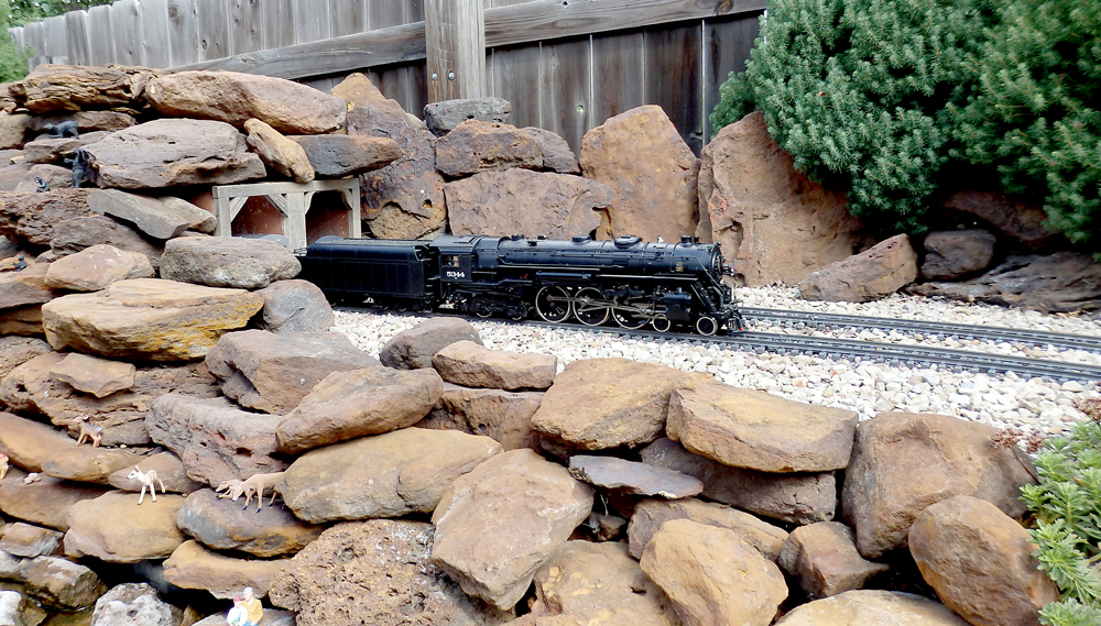 model steam engine exits a rocky tunnel