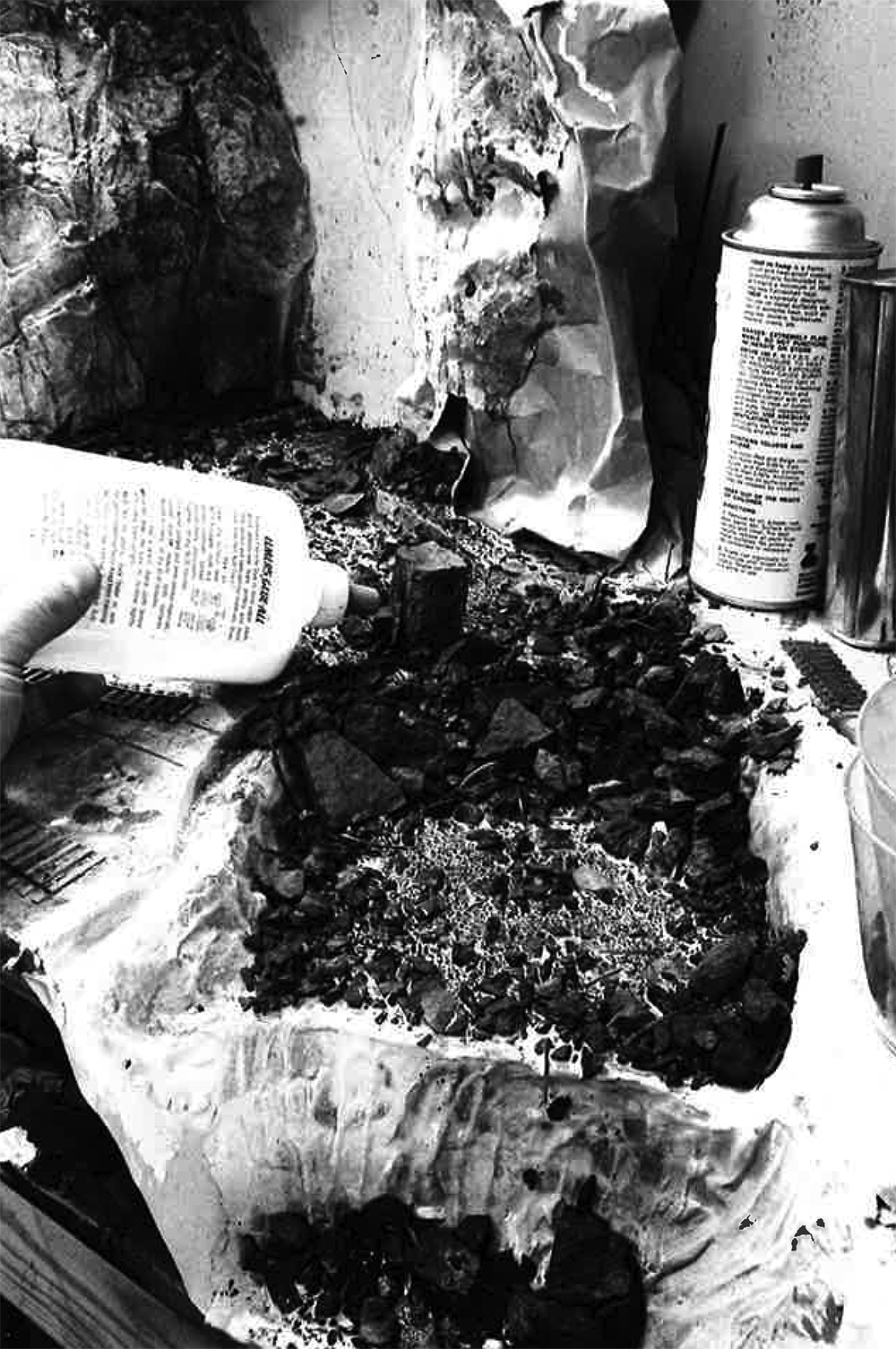 Malcolm Furlow's waterfall modeling technique: Black and white image showing rocks, dirt, and gravel being glued to a model railroad.