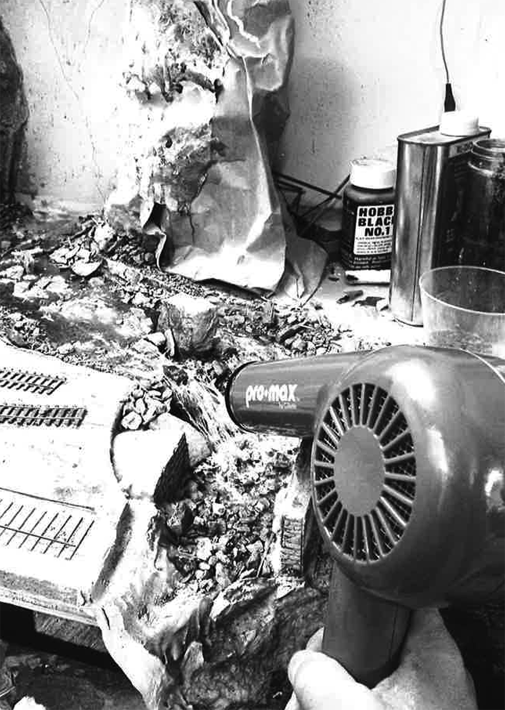 Malcolm Furlow's waterfall modeling technique: Black and white photo of hairdryer being used to cure resin being used as water on a model railroad.