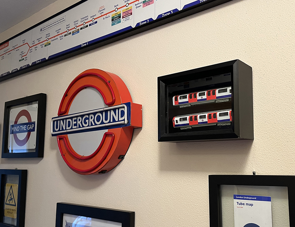 Red, blue, and white transit signs, some in black frames, on a yellow wall