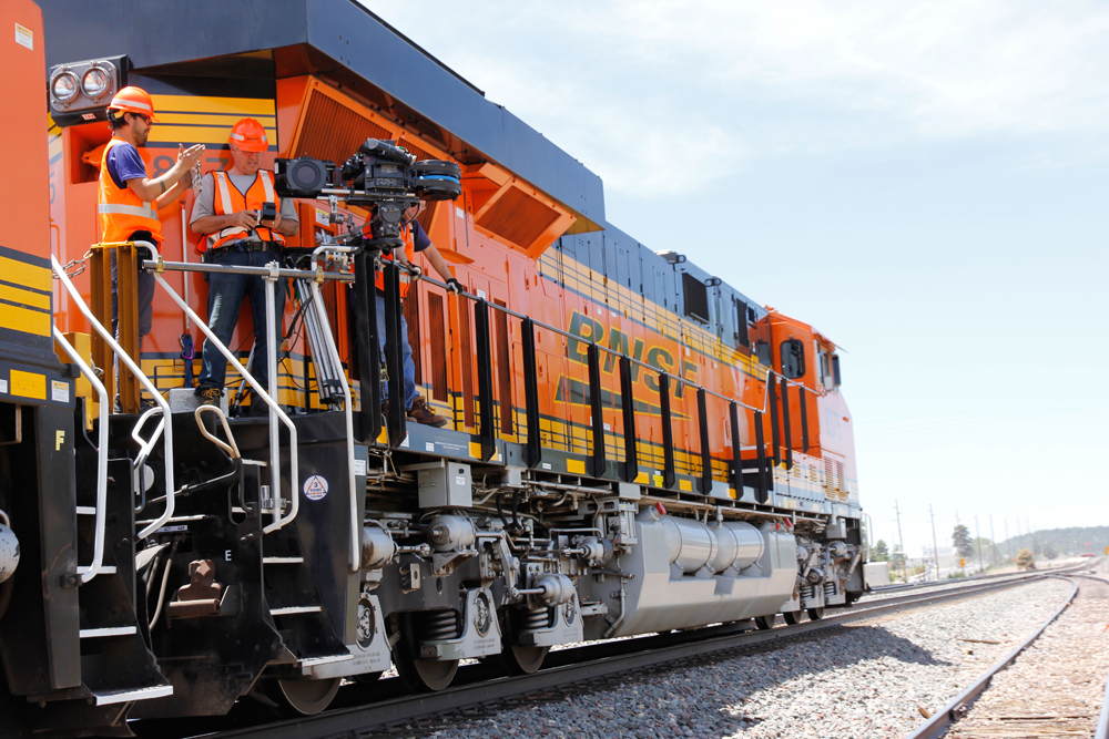 two men preparing camera on side of orange and black diesel