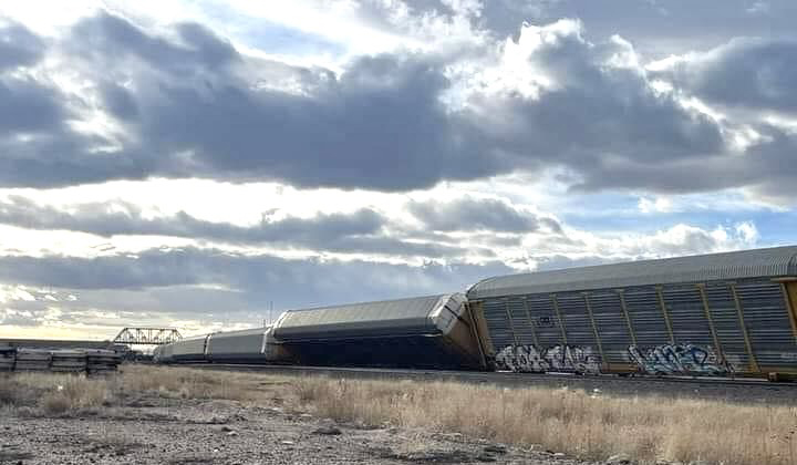 Derailed auto racks under cloudy skies