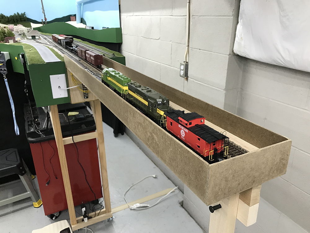 Carolina Sandhills Lines layout: Model train set showing a brown fold up shelf with track and brown, red, and green railroad equipment on it
