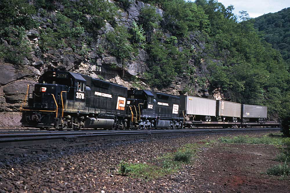 Penn Central locomotives on a freight train, one has an orange-and-white logo
