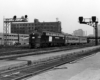 Black-and-white diesel locomotive with two passenger cars under elevated signals
