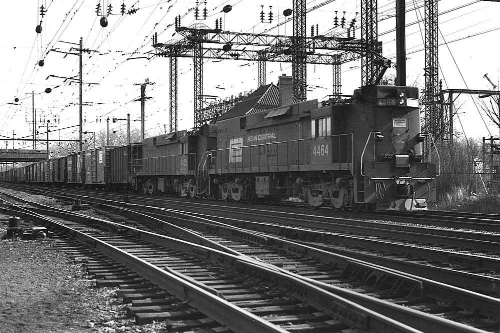 Two electric Penn Central locomotives with freight train under wires