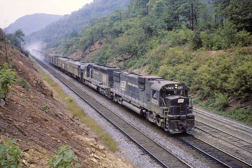Penn Central passenger train with smoking breaks rolls through mountain valley