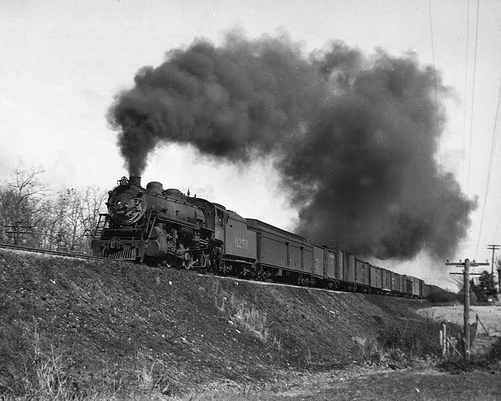 Smoking steam locomotive with train on embankment