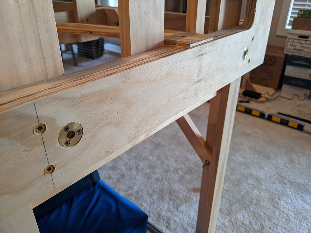 Two round brass washers countersunk flush in a plywood face