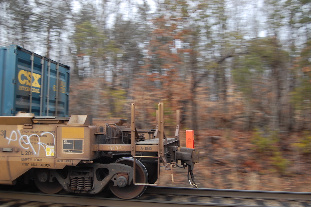 An orange end of train device is seen atop the rear coupler of a passing train