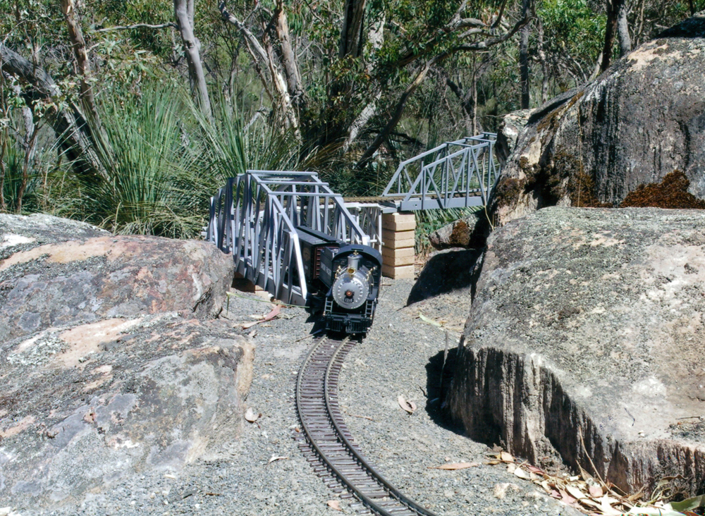 odel steam locomotive on track next to large rocks