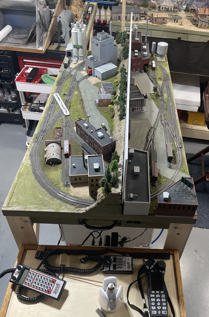 small toy train railroad as viewed from above showing how the oval of track is split by a scenery divider that runs through the middle of the table