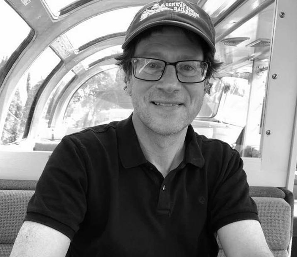 black and white photo of guy with glasses and hat on in train