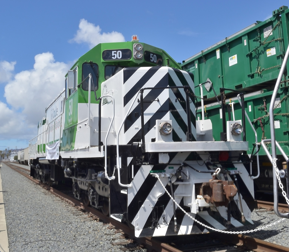 Front view of green and white locomotive with black nose stripes
