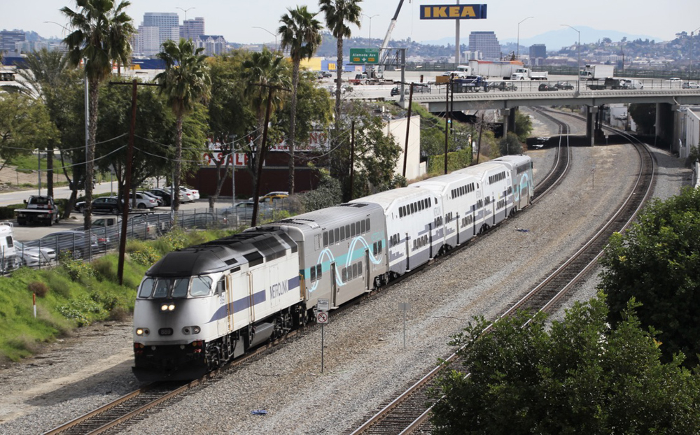 Commuter train led by white locomotive with blue stripe on curve