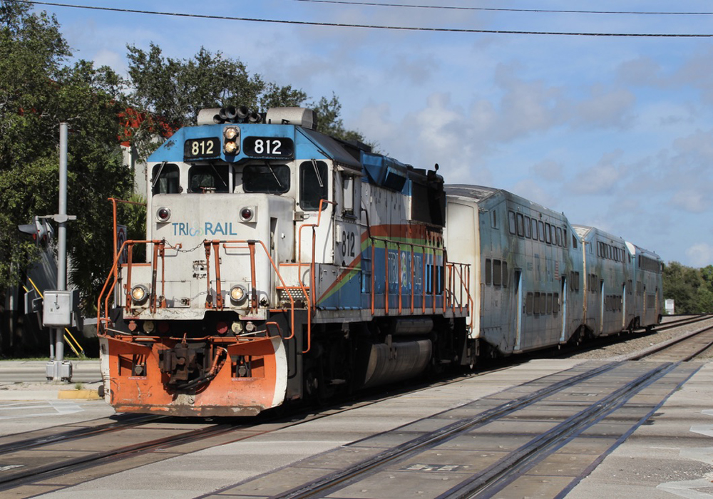 White, orange, and teal locomotive with bilevel passenger cars