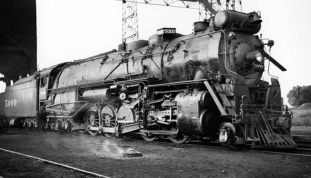 Steam locomotive parked in front of servicing structures