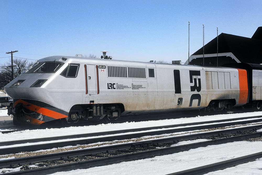 Silver, black, and red LRC diesel locomotive in front of station