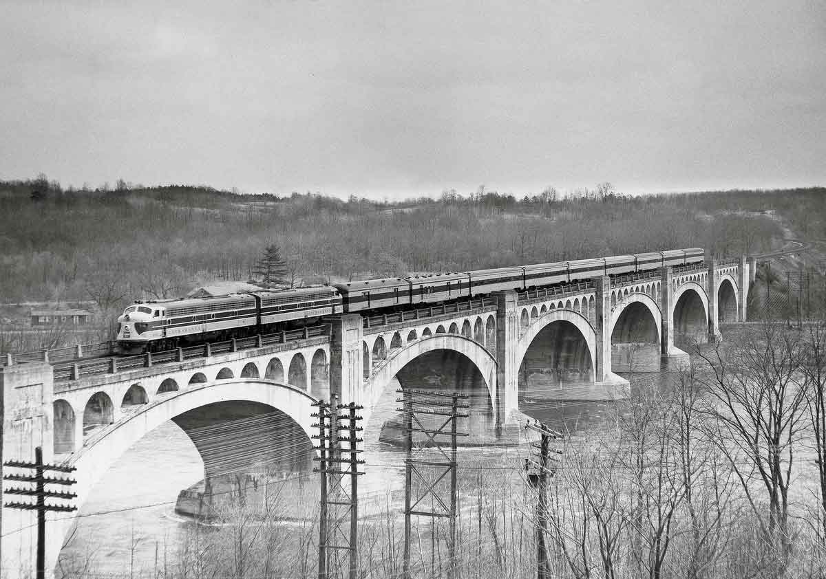 Streamlined diesel locomotives with passenger train on large concrete viaduct