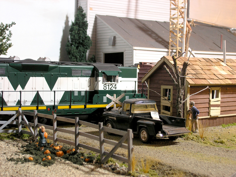 green and white diesel locomotive near grain elevator on garden railway