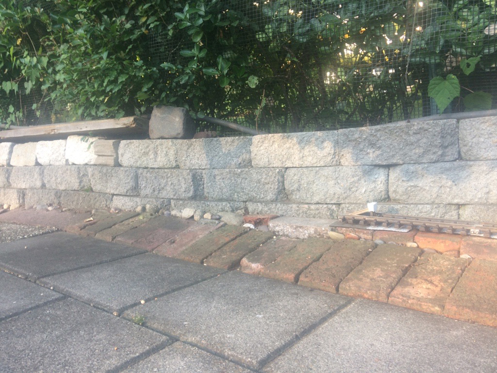 concrete pavers with fence and piece of track at right