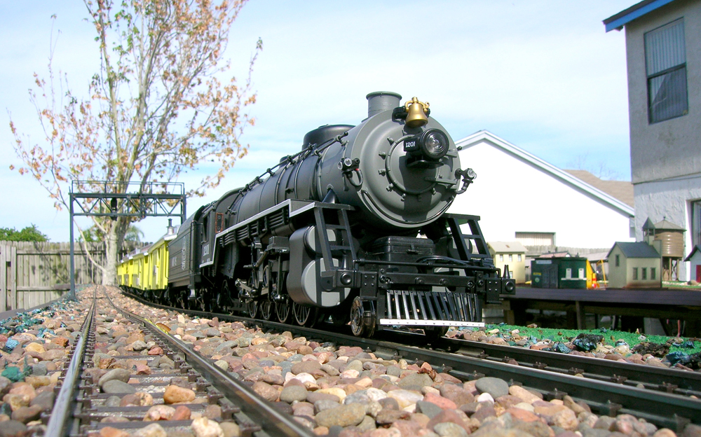 ow angled view of model steam locomotive on track of garden railway